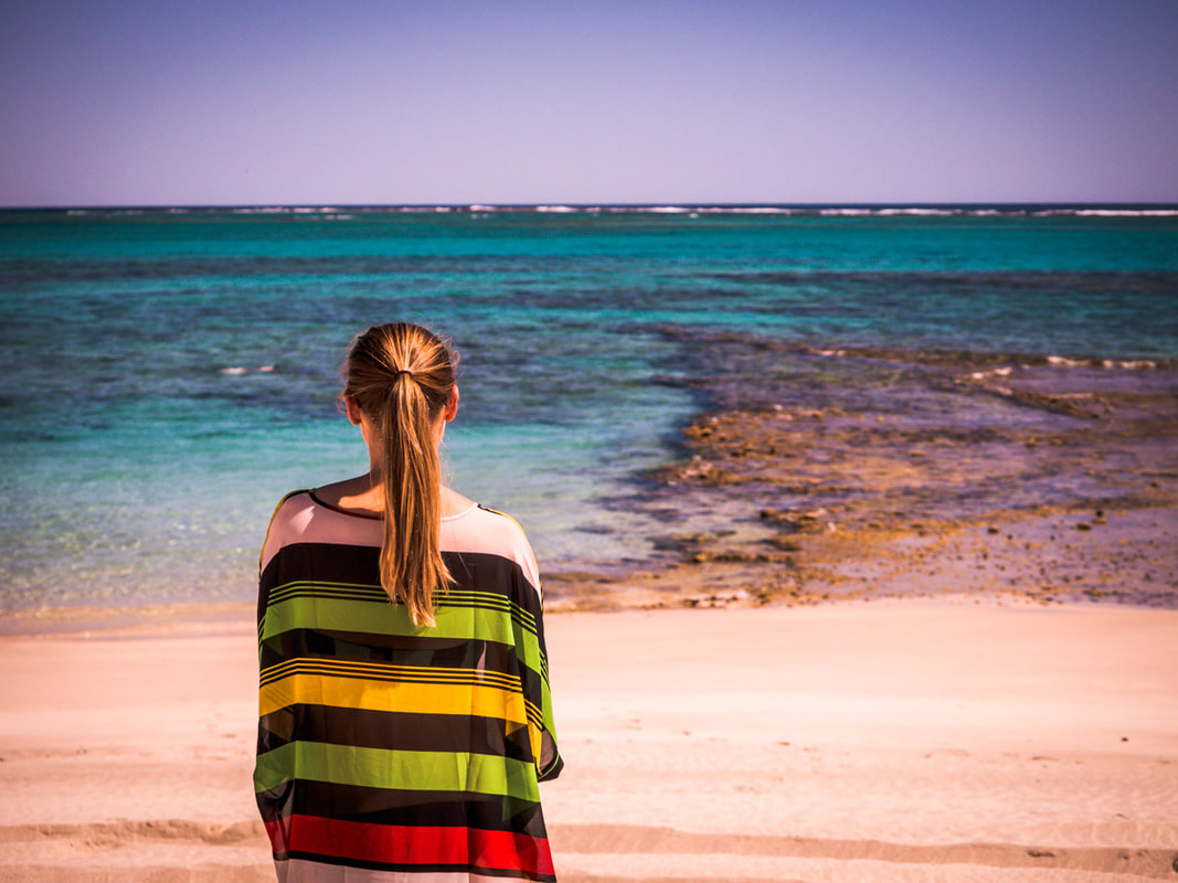 A woman in a colourful outfit looks out at the remote surf in Western Australia