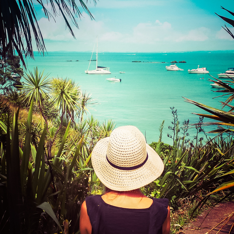 Picture of a woman with a sunhat overlooking the sea and boats on the island of Tiritiri Matangi in New Zealand 