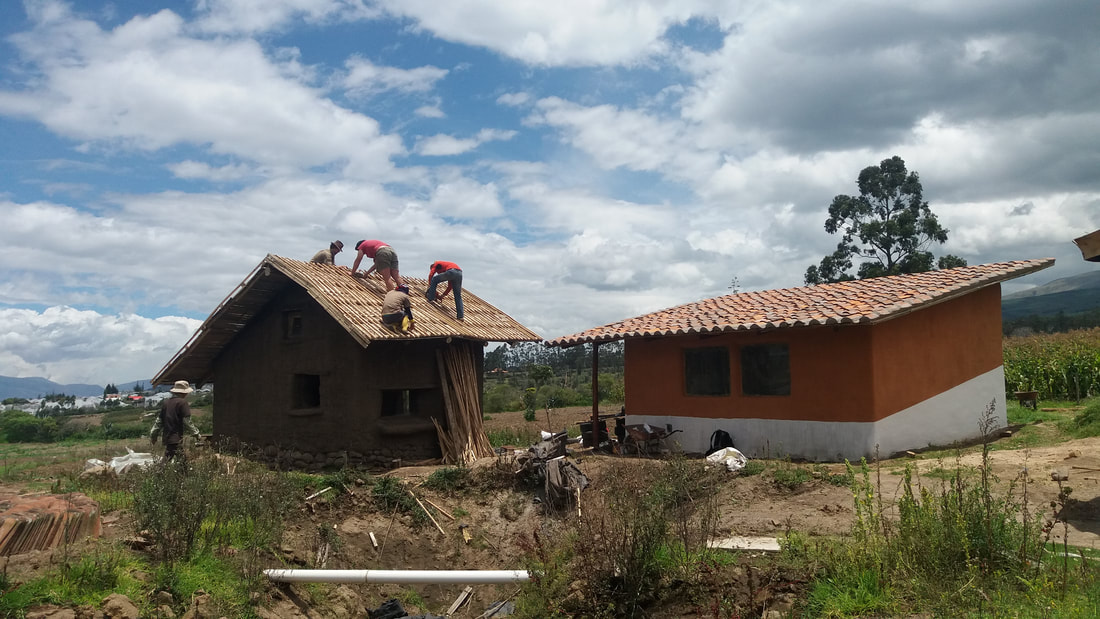 Four men building a roof on top of a house in Ecuador