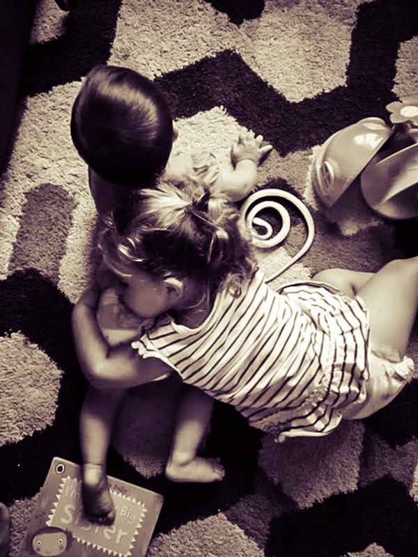 Picture of a little girls hugging her brother lying on a black and white carpet together 