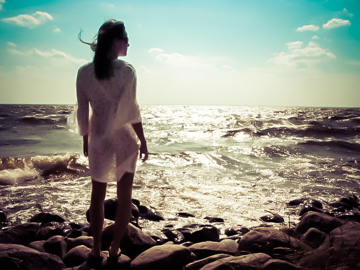 Picture of a woman standing on rocks and looking at the sea