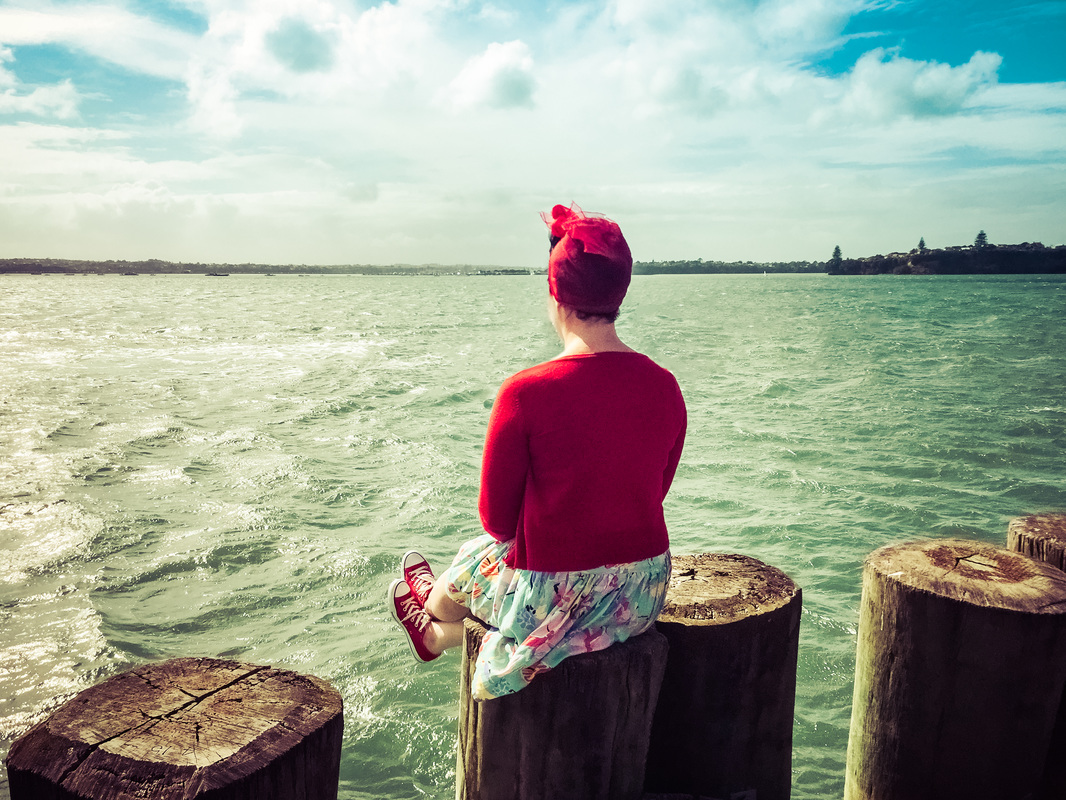 Picture of a woman sitting by the sea overlooking the water in New Zealand 