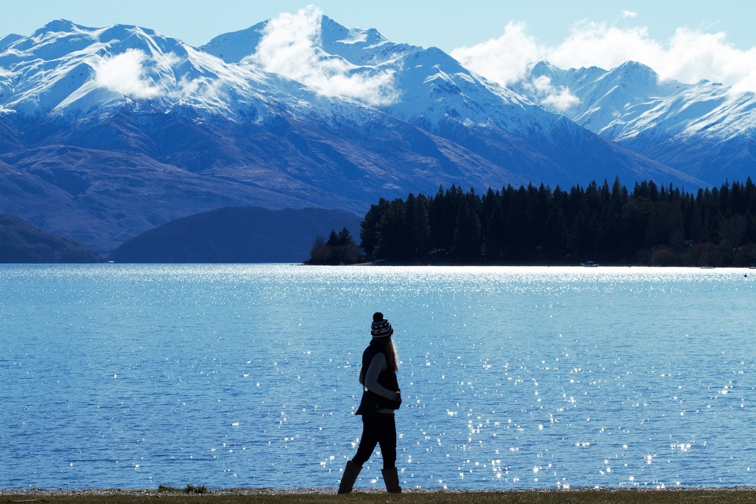 Picture of a woman standing at a lake looking at the mountains in New Zealand 