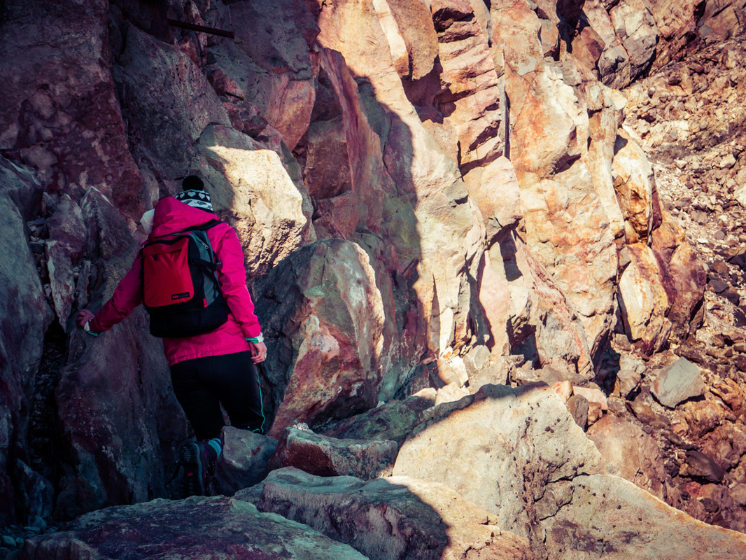Picture of a woman hiking up a mountain surrounded by rocks and big boulders