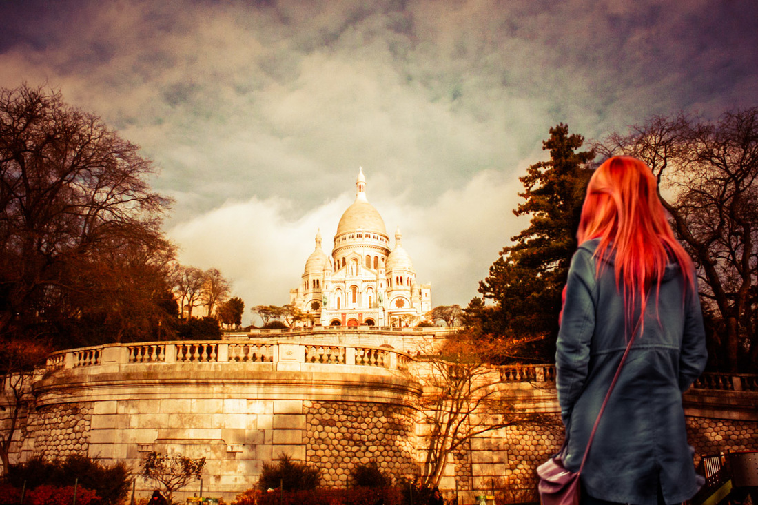 Picture of a girl with red hair and a blue coat looking at a church in Paris, France