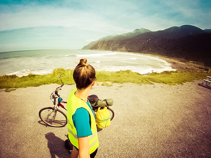 Picture of a woman standing in front of a bike overlooking a lake and mountains in South America