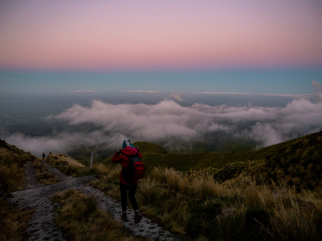 Picture of a woman walking down a mountain at sunrise 