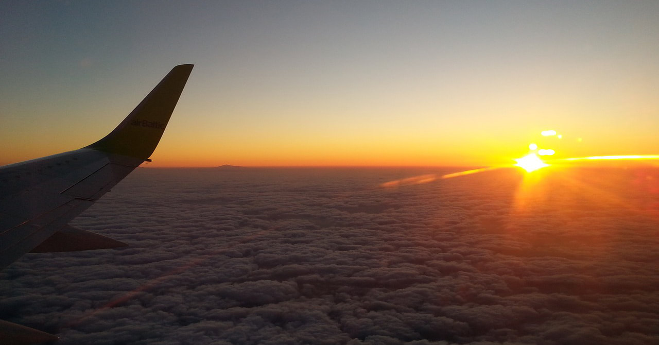 Airplane wing above the clouds at sunrise