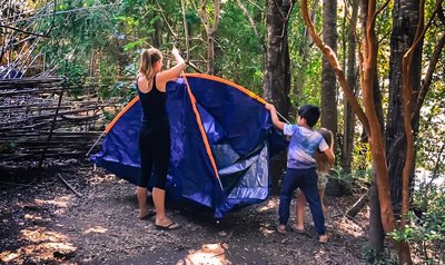 Woman and child setting up a tent in the woods