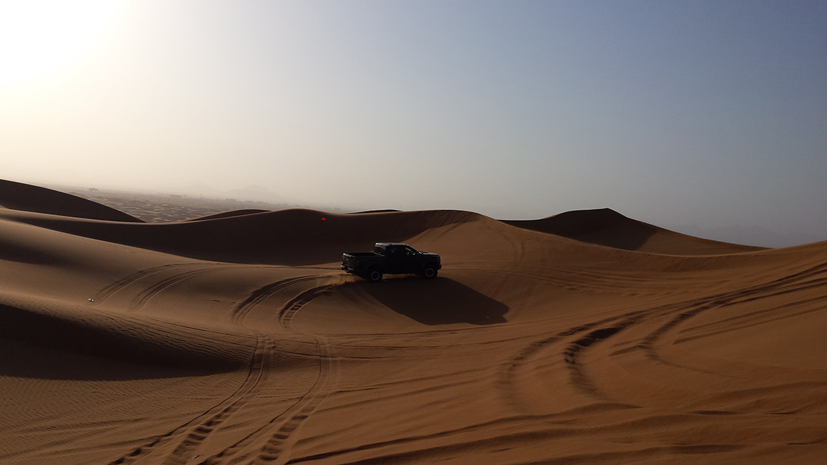 Picture of a black jeep driving over sand dunes in the Dubai desert