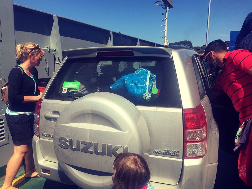 A family maneuvering around a packed car on a Chilean ferry