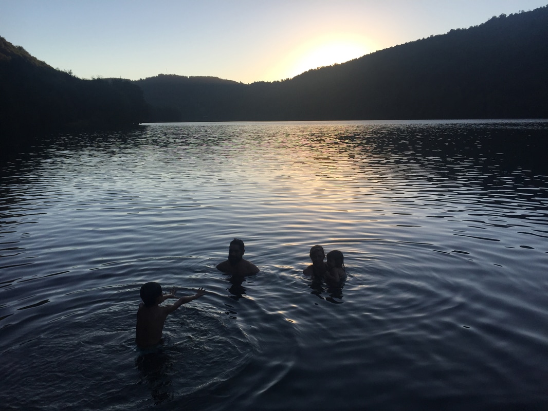 A family swims together in a Chilean lake at sunset