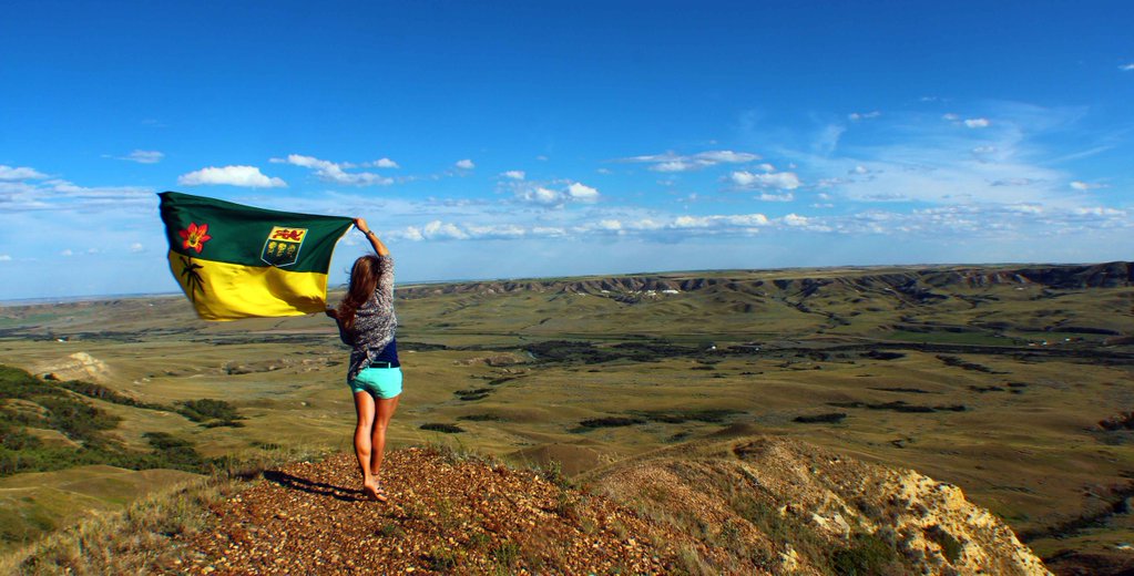 Woman stands with a Saskatchewan flag in Frenchman Valley, Saskatchewan