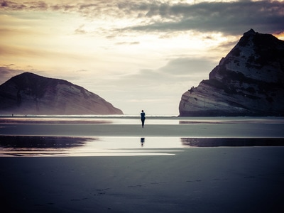 Woman stands on Wharariki beach in New Zealand