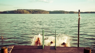 Friends jumping into water from a dock