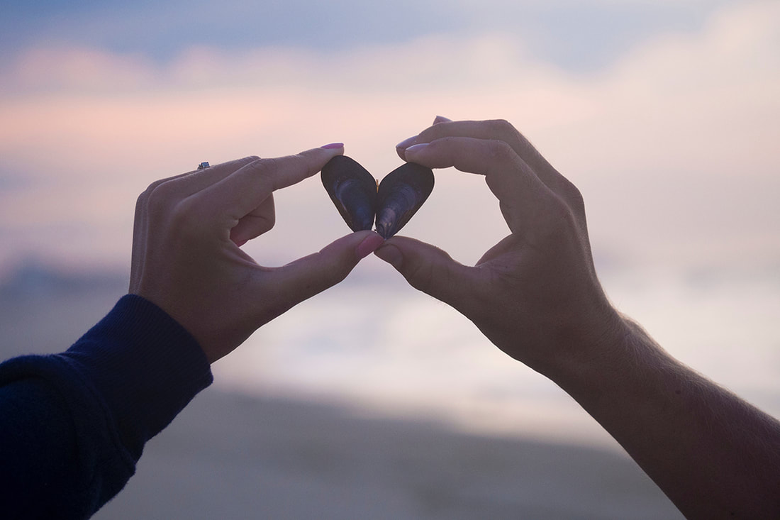 Male and female holding two rocks to make a love heart
