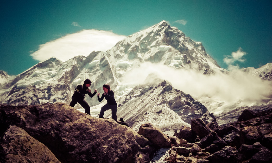 Two women fight posing with Himalayan Mountains behind them, en route to Everest base camp