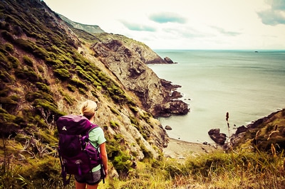 Woman in a backpack overlooking rocky seascape