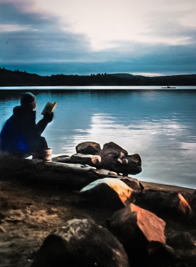 Woman reading beside a lake in cold weather