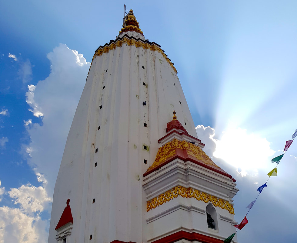 The white Buddhist temple Swoyambhunath Stupa in Kathmandu, Nepal on a sunny day with clear blue skies in the background