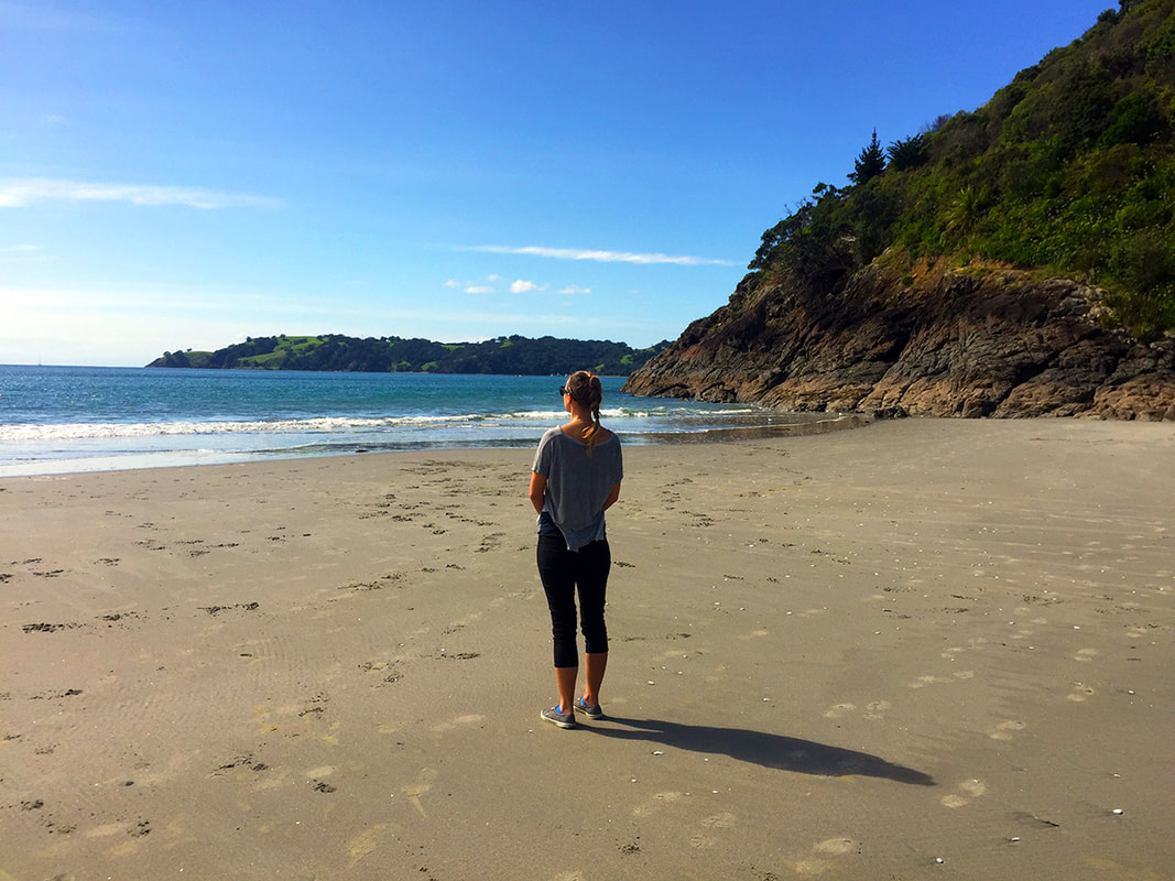 Woman stands overlooking beach on Waiheke Island, New Zealand