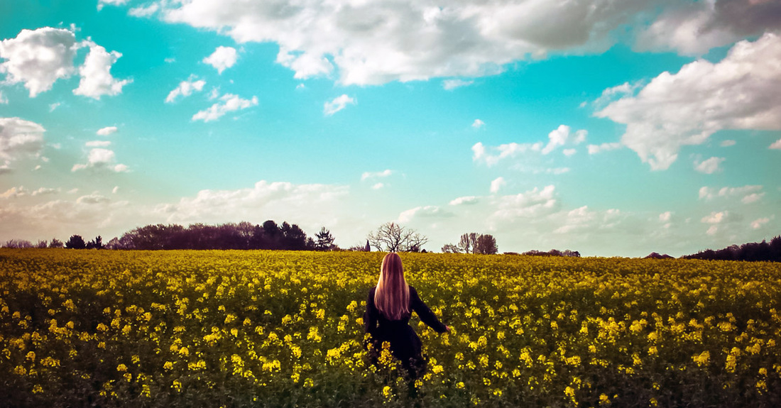 Woman stands amongst thousands of wild yellow flowers